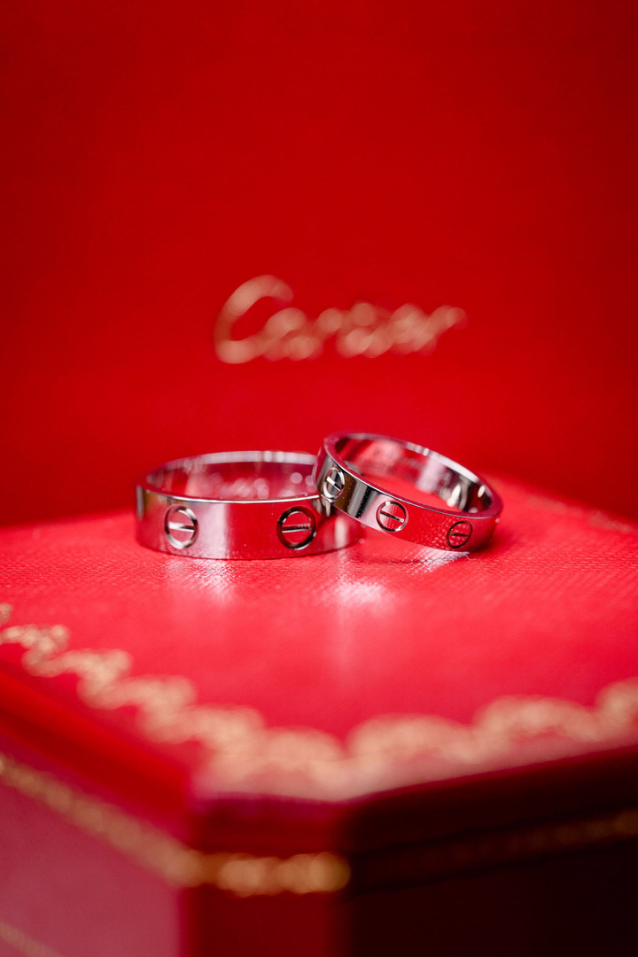 Cartier wedding rings placed on a red box with a golden ornament and the Cartier logo.
