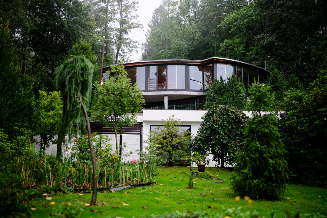 The wedding venue Resort Cattaleya and its green garden, with tall trees and mist in the background.
