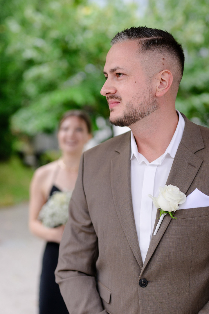 Groom looking for the bride and smiling.
