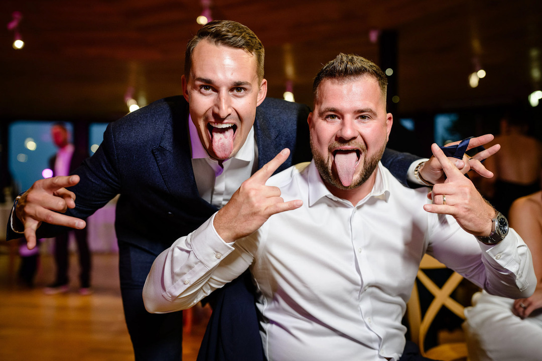 Two men sticking out their tongues and posing for the camera.
