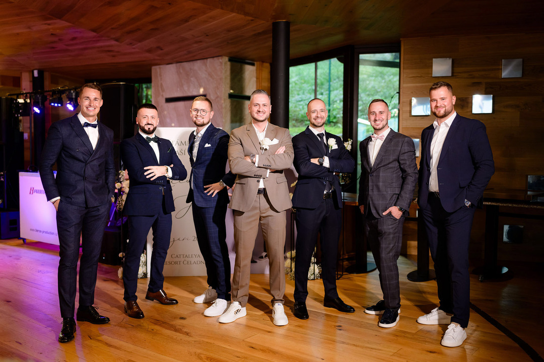 The groom poses with his friends, standing in the foreground in a brown suit. Behind him, the men are dressed in dark suits, wearing serious and tough expressions.
