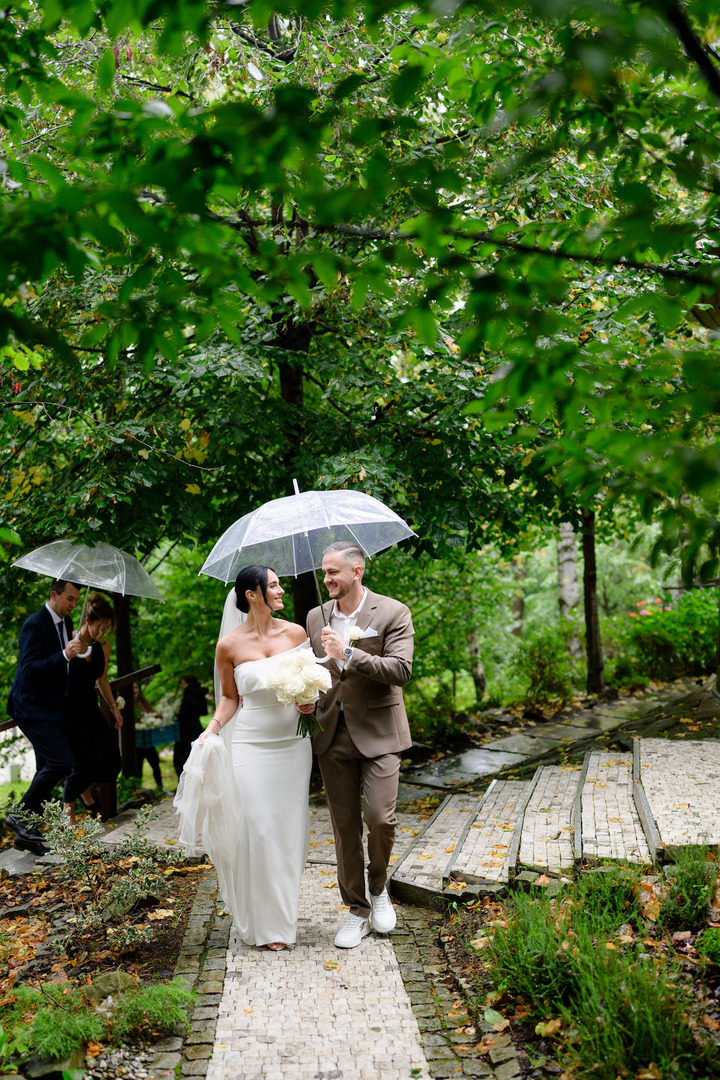 The newlyweds walk happily through the garden of Cattaleya Resort, holding an umbrella above their heads.

