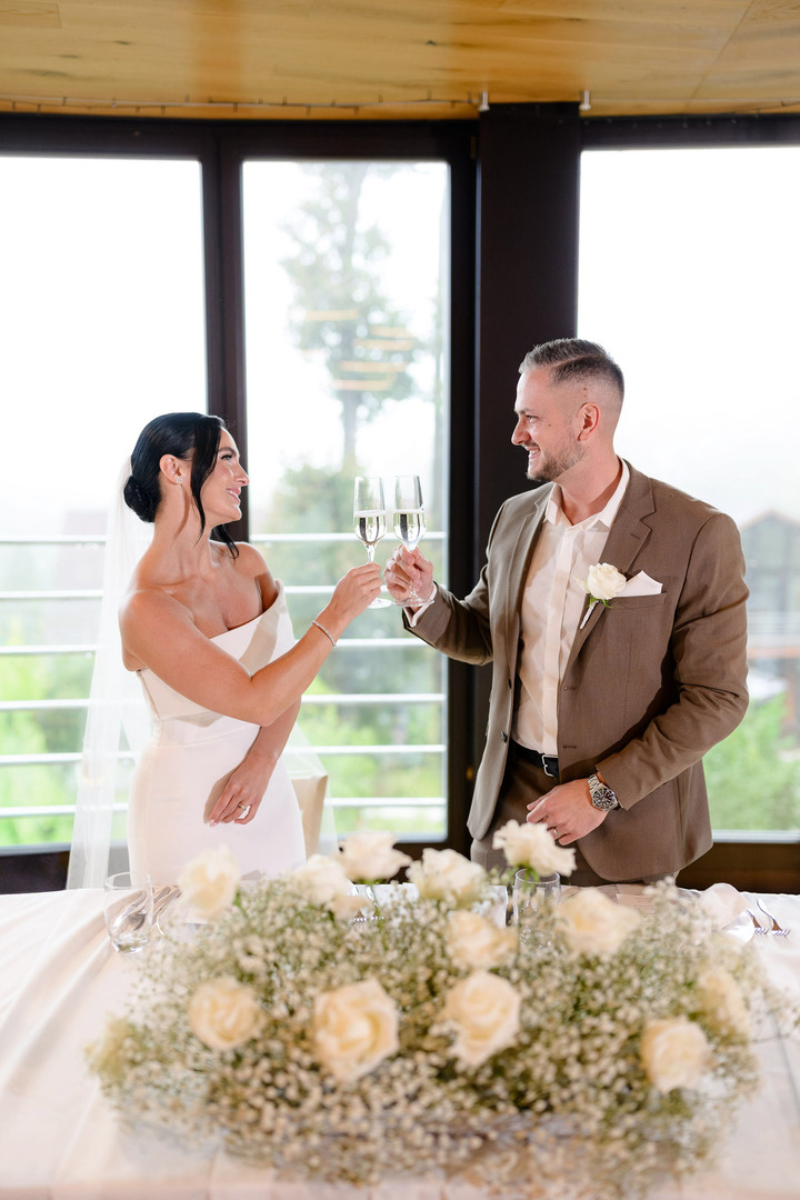 The bride and groom toast, gazing into each other's eyes and smiling at one another.
