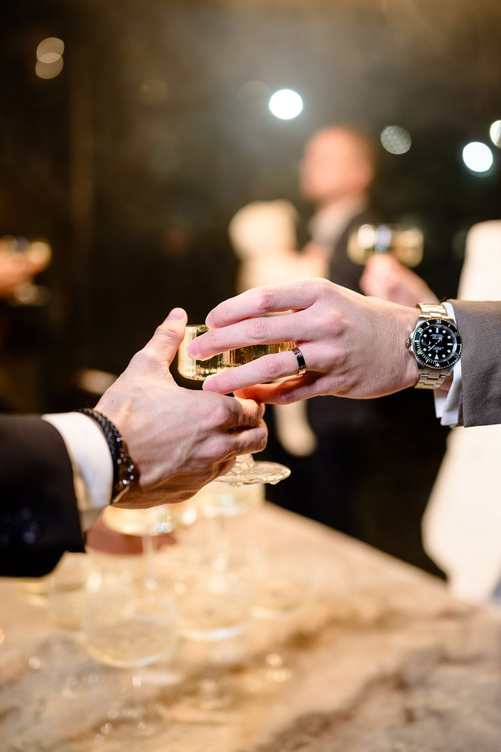 Close-up of hands passing champagne to each other.
Close-up of hands passing champagne to each other.
