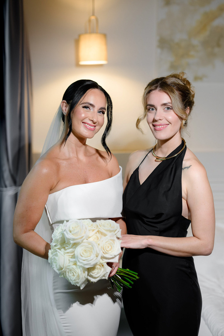 Nevěsta se objímá se svou sestrou a usmívají se do fotoaparátu.