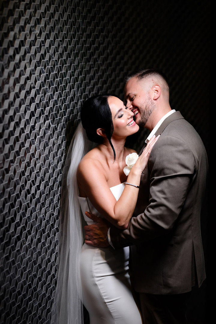 Bride and groom in a close embrace, playfully teasing each other, laughing and enjoying their shared moment.

